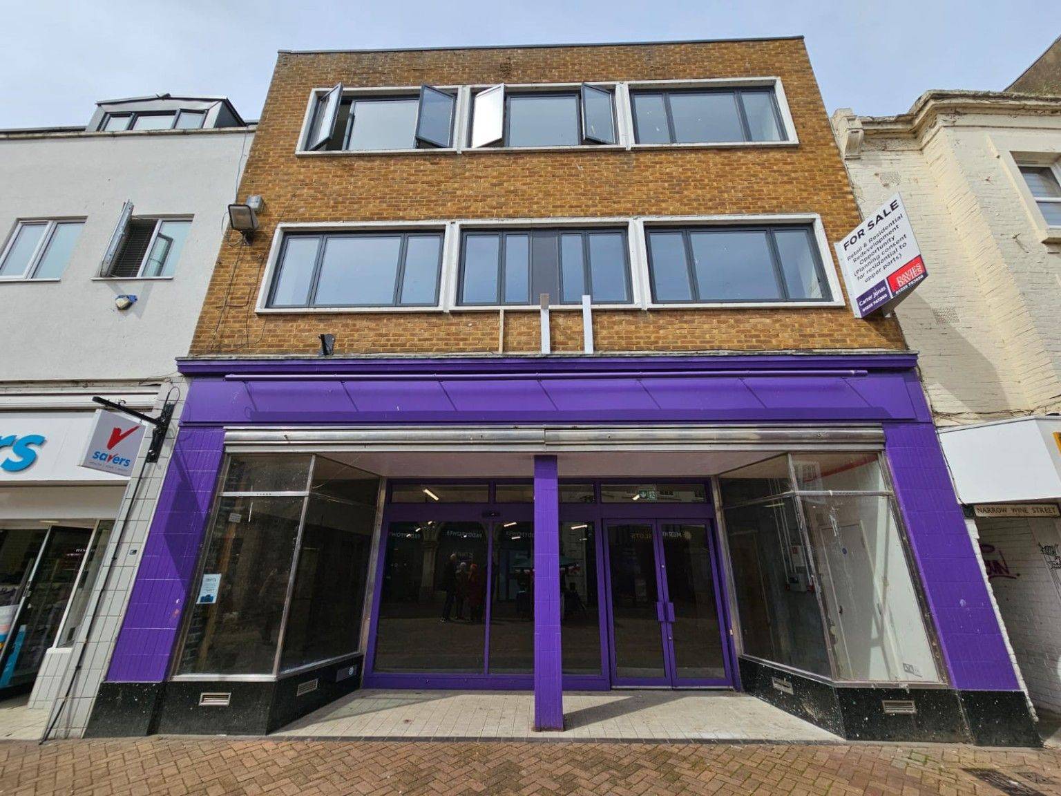 The frontage of 32 Fore Street, Trowbridge — purple shopfront with a blank fascia and glazed double doors onto the pedestrianised street