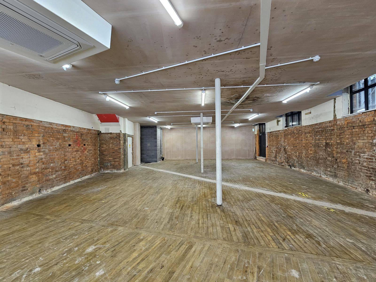 Rear of the unit showing exposed brick and ceiling-mounted air conditioning